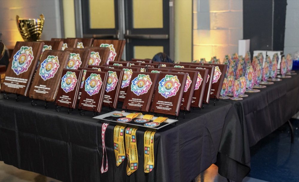Medals, plaques, and trophies laid out at the CIC 2026 award ceremony at Century Gardens Recreation Centre